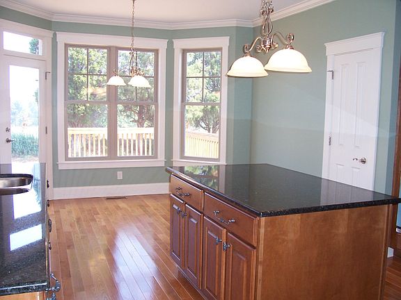 Kitchen has granite, island, tile backsplash, ss appliances, hardwoods, pantry