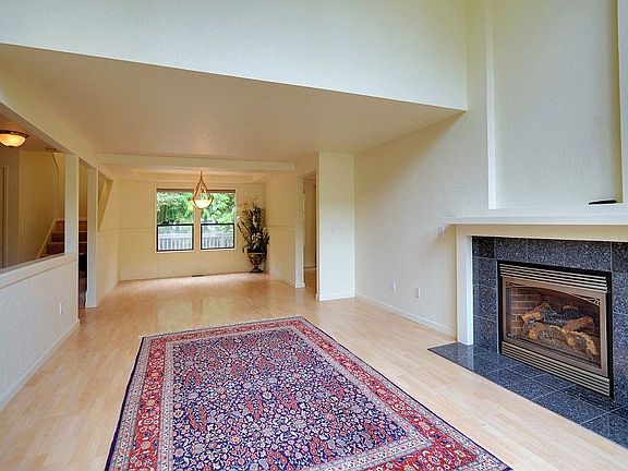 View of Living Room to Dining Room area. Modern light fixtures, easy to maintain laminate flooring. Living Room features soaring ceiling.Gas Fireplace in the living room with beautiful Granite Tile Surround and Mantel.
