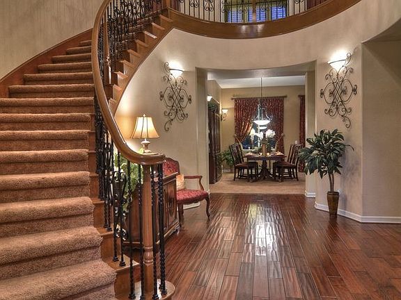 Grand Foyer showcasing Sweeping Staircase with Rod Iron Balusters.