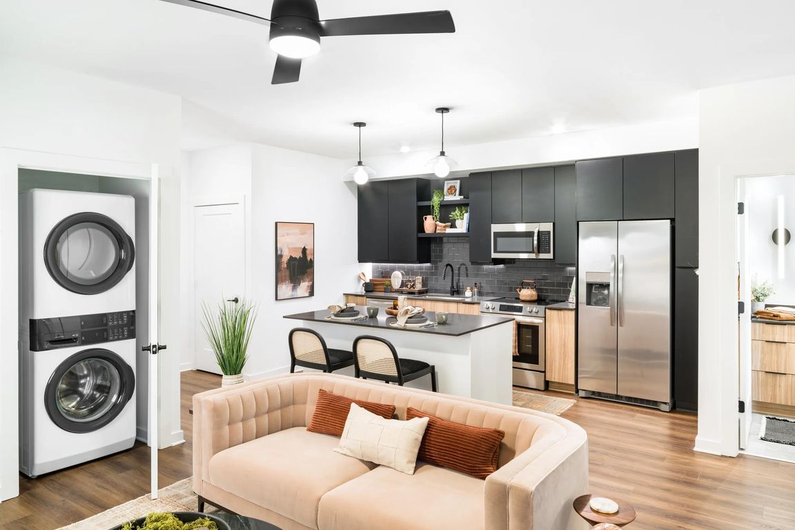 An open living area at Modera Nations in Nashville features wide-plank flooring, an island kitchen, and in-home laundry for seamless everyday living.