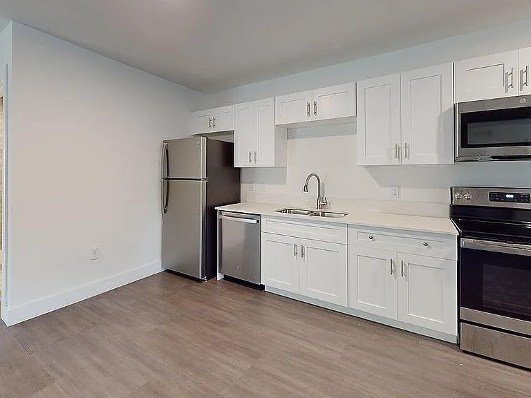 Modern kitchen with sleek stainless steel appliances, elegant white cabinetry, and polished countertops, offering a contemporary and functional space.