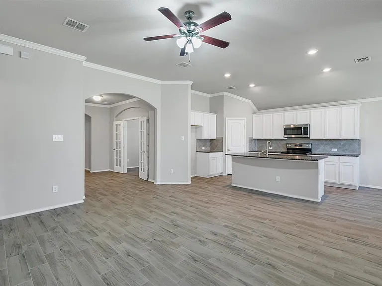 Open-concept living area featuring wood-finish flooring, recessed lighting, and crown molding