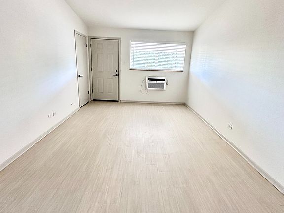 Bright and inviting room with sleek flooring, large window, and modern air conditioning unit.