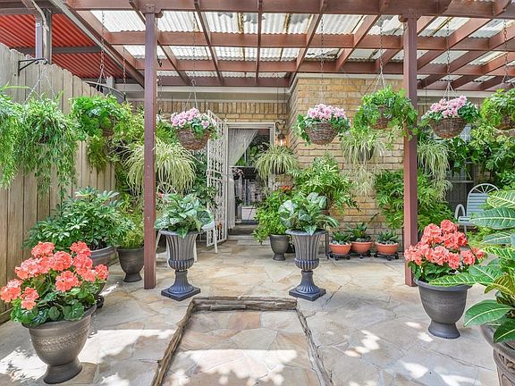 Beautiful outdoor living area with gorgeous flagstone patio that leads to reserved, covered parking for two cars, additional storage and convenient back gate trash pick up.