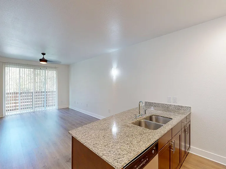 Apartment kitchen with stainless steel appliances and wood style floor.