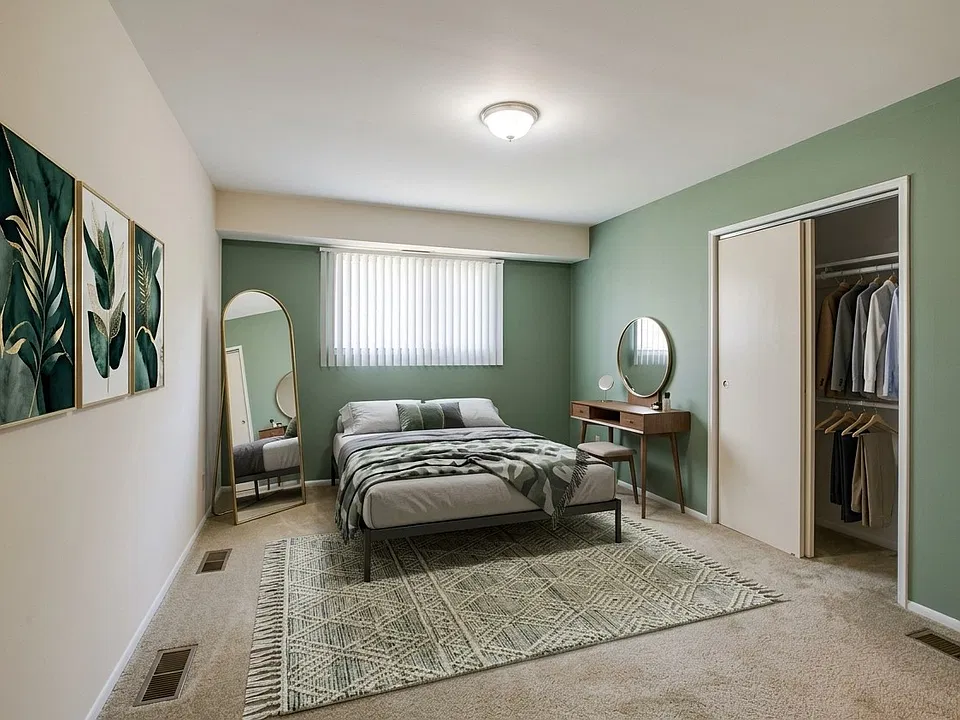 A serene Woodmere Apartments bedroom features neutral tones, plush carpeting, a ceiling fan, and a private bathroom entry. View available homes and schedule your tour today.