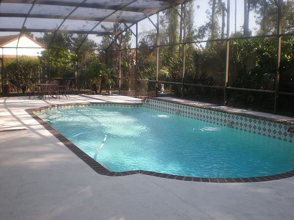 A view of the screened-in pool and backyard, from behind the master bedroom.