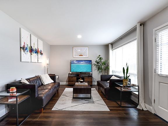 Living area featuring baseboards, dark wood-style flooring, and a wealth of natural light