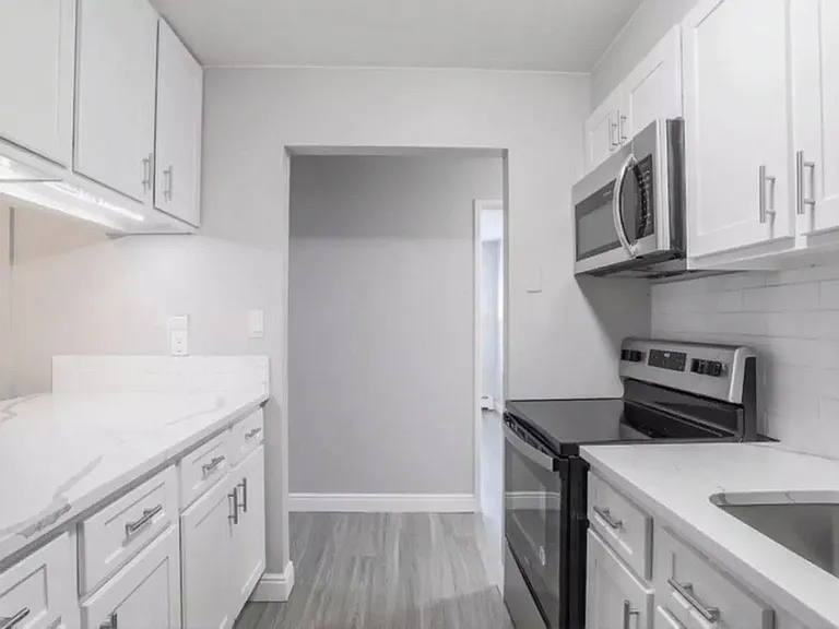 Modern kitchen with sleek white cabinetry, stainless steel appliances, and elegant countertops.