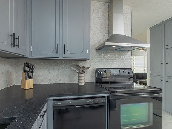 Fully stocked kitchen with a stainless steel range hood and cooking essentials