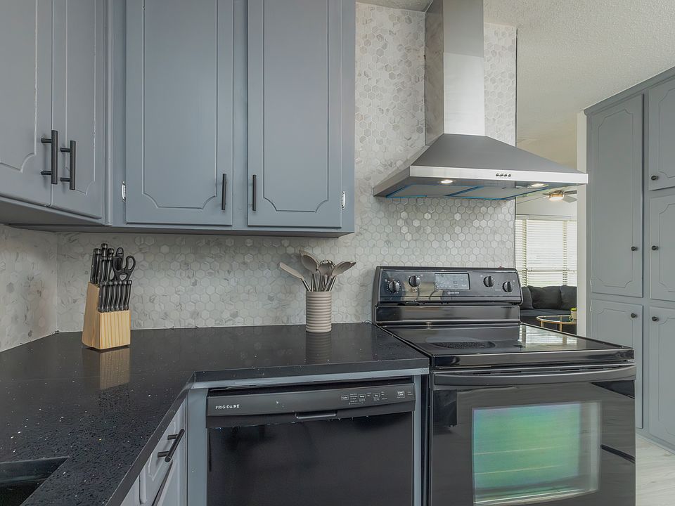 Fully stocked kitchen with a stainless steel range hood and cooking essentials
