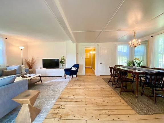 Expansive living and dining room with rustic, wide plank wood flooring.