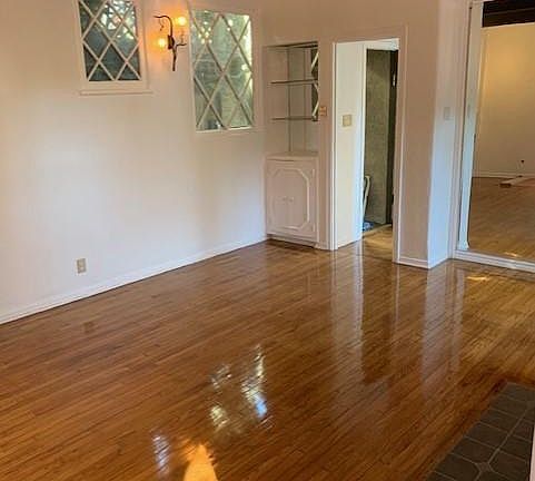 Older photo when apartment was painted white, I can do it again. Another view of the living room, and entrance door. Living room enjoys two diamond shaped windows, open shelving and storage cabinet.