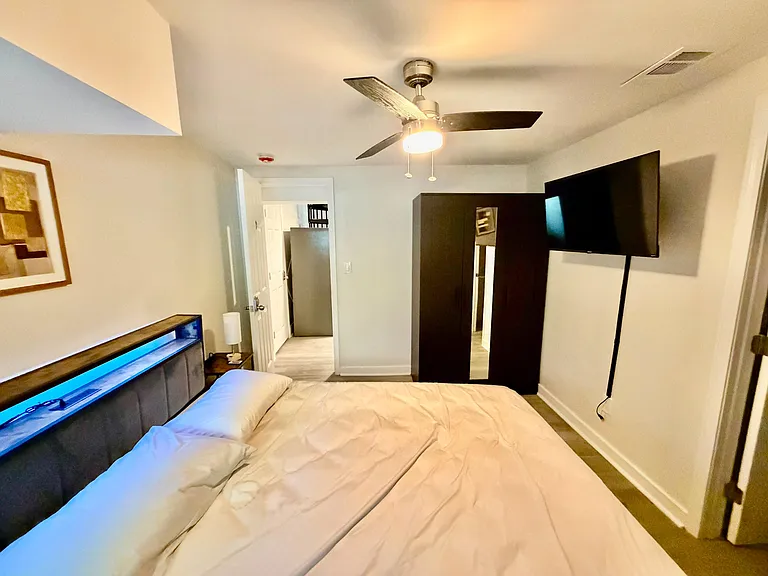 Furnished bedroom with a comfortable bed, wardrobe storage, ceiling fan, and wall-mounted TV for easy everyday living.