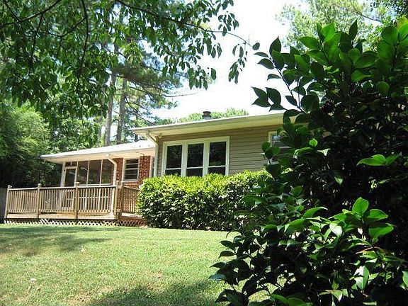 Rear wood deck and screened porch overlook rolling wooded back yard.