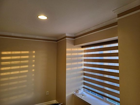 Living room with smart zebra blind that matches the wall color and can be controlled by remote and voice command