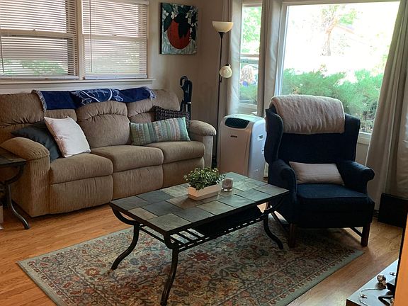 Living room with wood flooring and drapes/blinds included