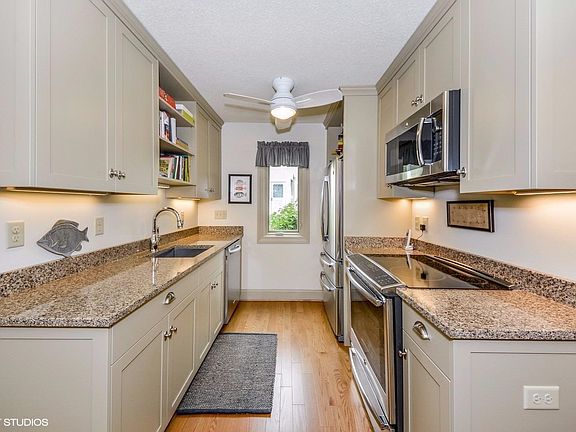 The gorgeous kitchen features custom cabinetry, quartz countertops, newer stainless appliances, unde
