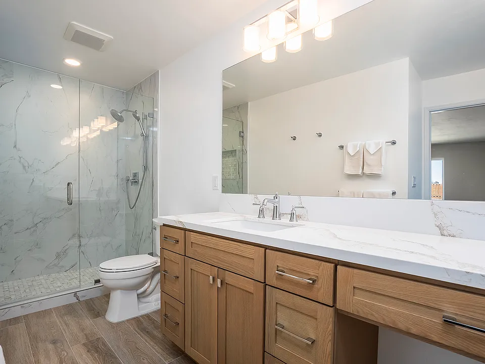 Newly remodeled primary bathroom, including custom cabinetry, 30" knee-hole vanity, large-scale porcelain tile walk-in shower, and top-tier plumbing fixtures.