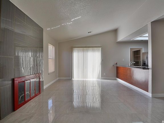 Sleek tile floors in living room with vaulted ceiling, dining bar, and updated fireplace area.
