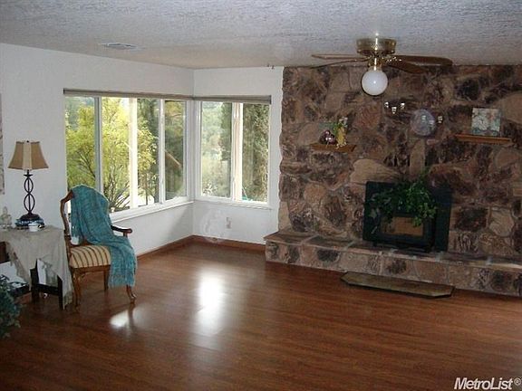 Large living room with a stone fireplace, built in oak cabinets and views.