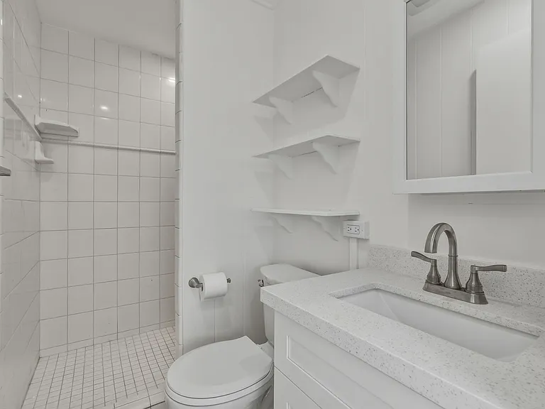 The bathroom features a new vanity and toilet. The walk in shower is tiled.