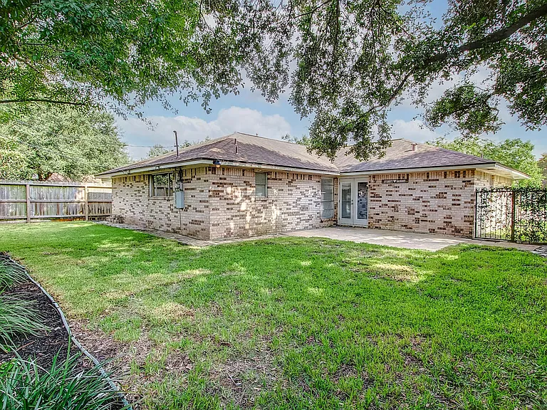 fenced backyard is shaded and has patio w/french doors