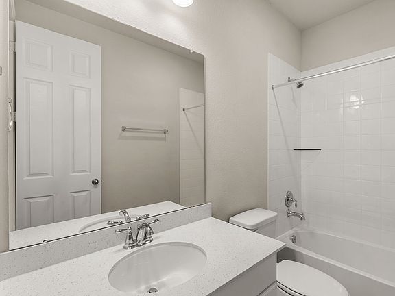 The secondary bath features tile flooring, white cabinetry and light countertops and a shower tub co