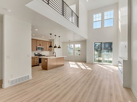 Spacious modern kitchen and living area with high ceilings, large windows, light wood flooring, and