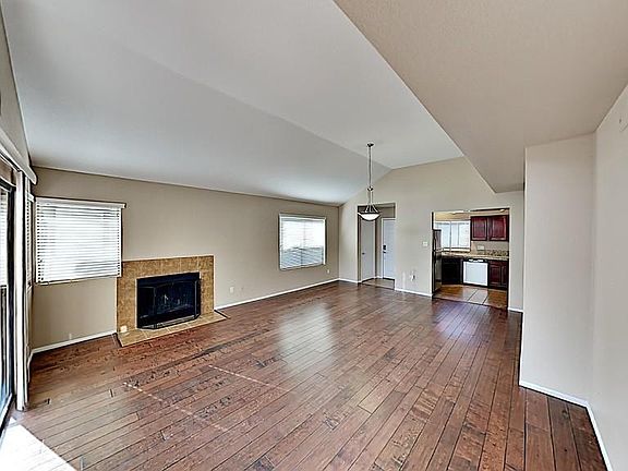 Large great room with vaulted ceilings and a tile-wrapped fireplace. Everything is clean and freshly painted.