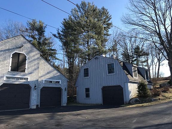 View of the waterfront cottage (right) with garage level storage and parking as well as an outdoor parking space (in front of barn door next to the cottage).