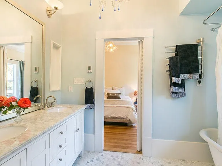Bath ensuite to master and back bedroom. Italian chandelier jack and jill with two sinks, heated floor, claw foot tub and designer toilette. White marble floor and vanity.