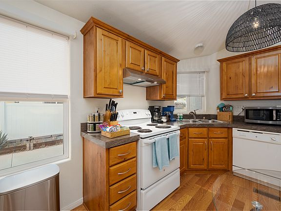 This kitchen is fully equipped with essential appliances, including a white electric stove, dishwasher, microwave, refrigerator, and both a Keurig and traditional drip coffee maker to start your mornings right