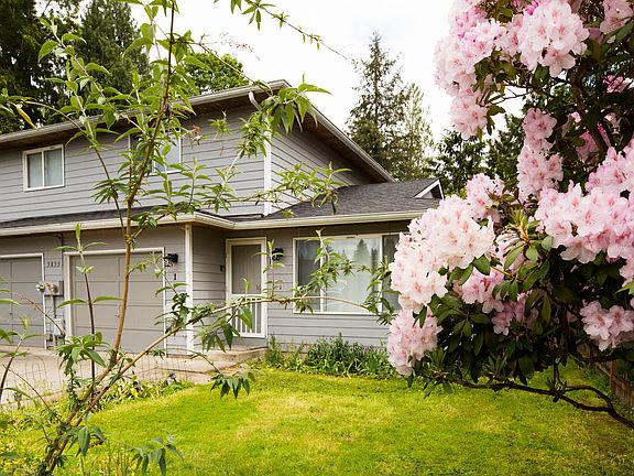 Front yard and exterior surrounded by mature landscaping and flowering trees, creating a peaceful and private residential setting.