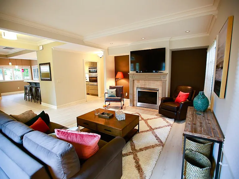 Corner view of the large living room that opens up into the eating area and kitchen bar with stools.
