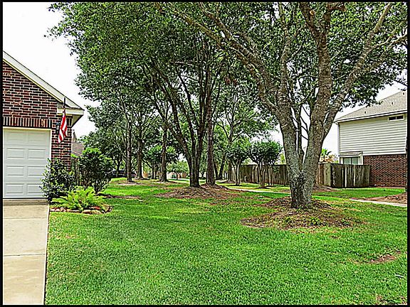Walk path between houses with mature trees.