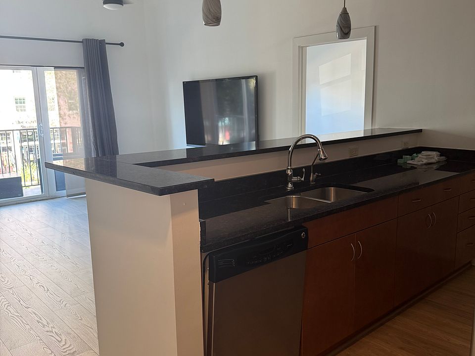 Full-sized kitchen with microwave, oven, fridge, and dishwasher, plus ample storage on both sides and a built-in 4-top bar seating area.