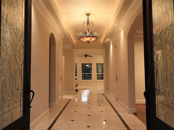 SOPHISTICATED FOYER WITH TRAVERTINE FLOORS AND COVE LIGHTING - Past the double lead glass front doors is this engaging entry with barrel ceiling and cove lighting. The unique pendant and wrought iron chandelier is delicately made with plant leaves.