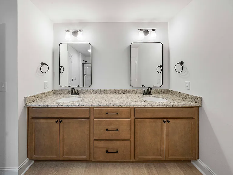 Primary bath features dual vanity with granite countertops and matte black accessories