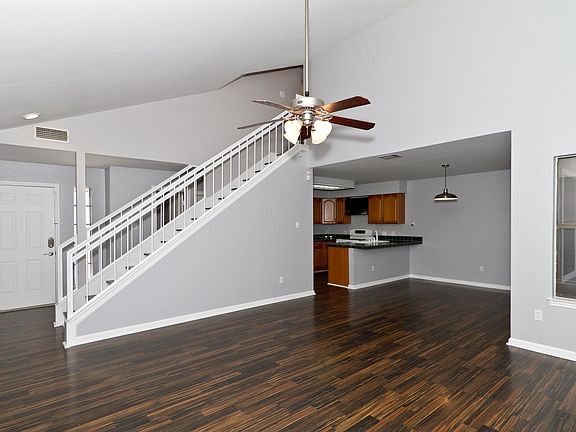 Front door at left into living room. At right, dining and kitchen. Vaulted ceiling in living room goes up to second floor with stairs. On the other side of the stars is a hallway with half bath and garage access.