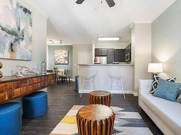 Apartment Kitchen with Stainless Steel Appliances, Dining and Living Room with Wood-Style Flooring.