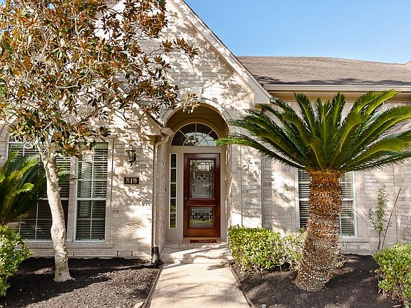 A bricked & arched front porch with a brick floor and coach lanterns grace the front of this home.