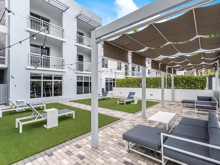 Ground-Level Green Space with Lounge Chairs and Walkways Next to Residential Windows
