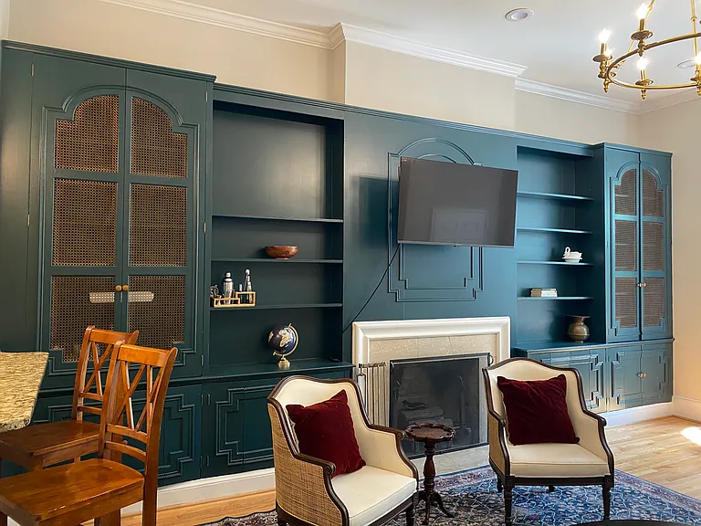 A wall of attractive built-ins, working fireplace, smart TV, new sofa and side chairs, contemporary chandelier.