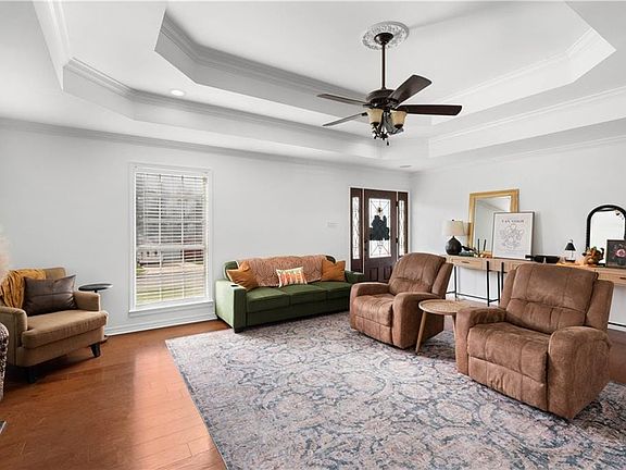 Living room featuring wood-type flooring, ornamental molding, and ceiling fan.