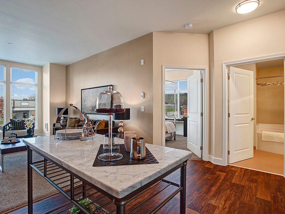 A view of the kitchen island with the living space, bathroom, and bedroom in the background