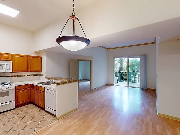 Apartment kitchen, dining and living room with wood-style flooring.