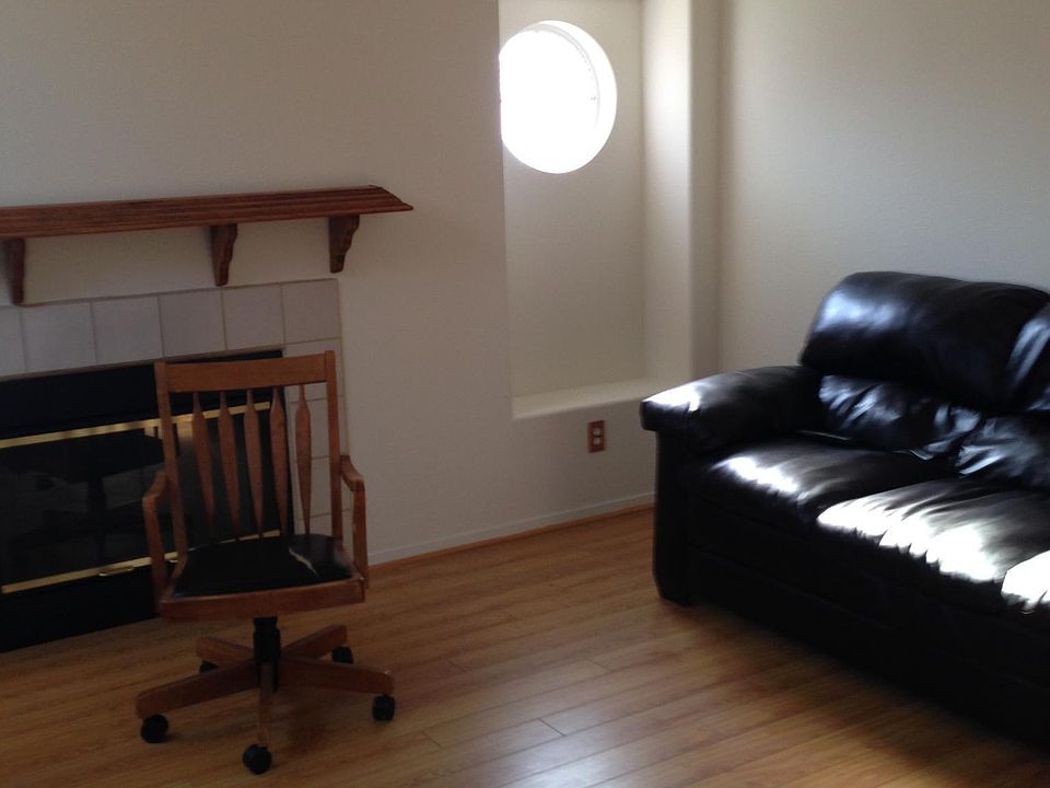 Living room with wooden floor, ceiling fan, and gas fireplace