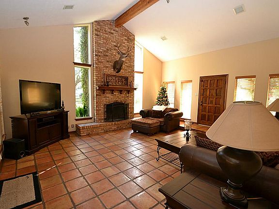 Spacious family room featuring Saltillo tile floors, cathedral ceilings, wood burning fireplace and 