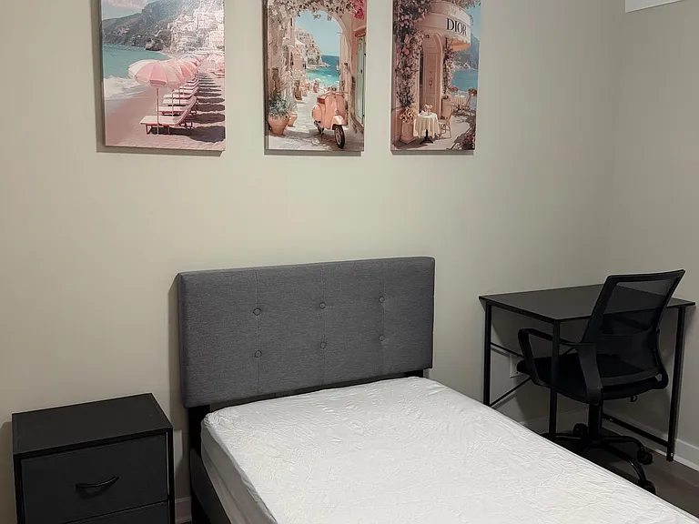 Furnished bedroom with a comfortable bed, nightstand, and a dedicated desk setup for work or study.